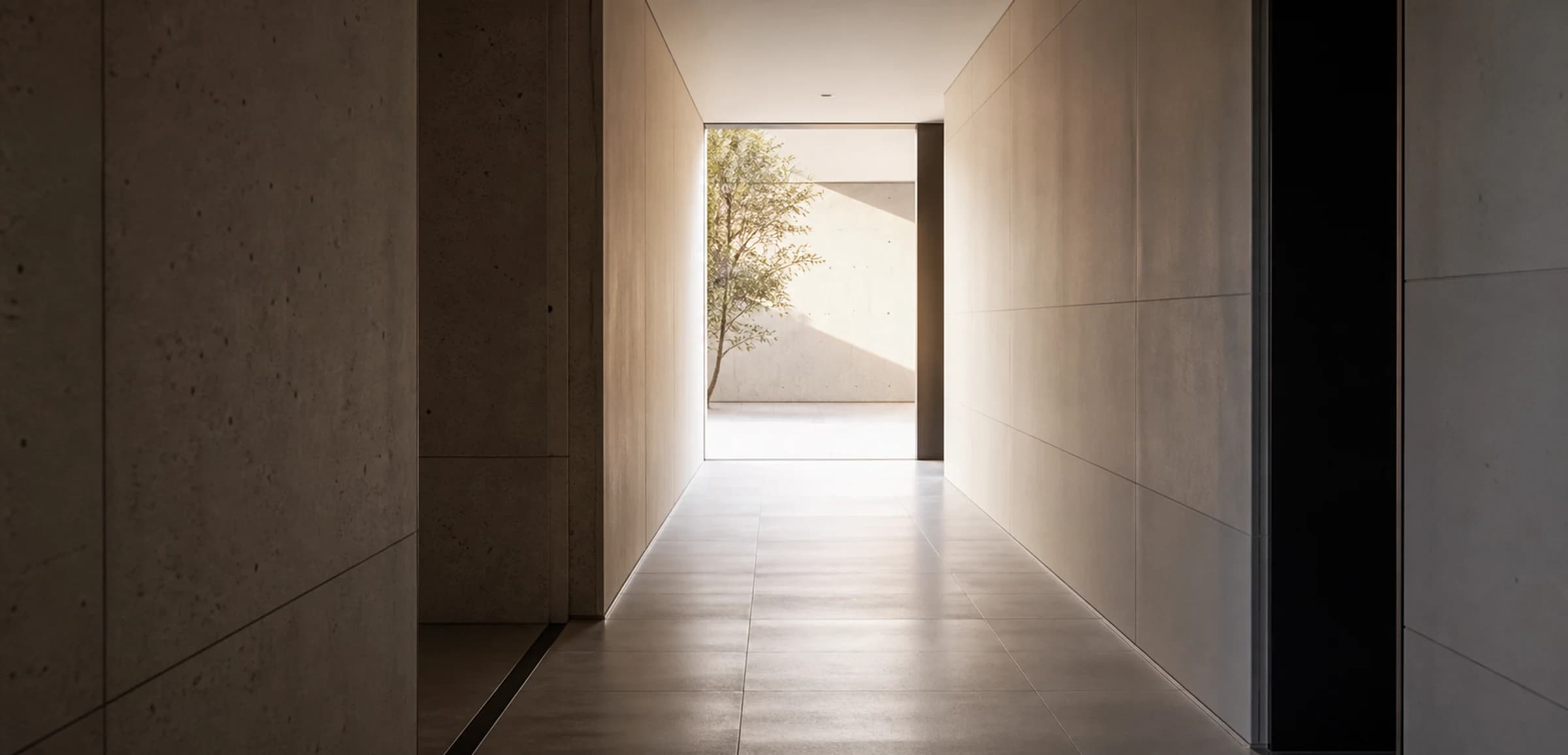 An empty architectural corridor leading toward daylight.